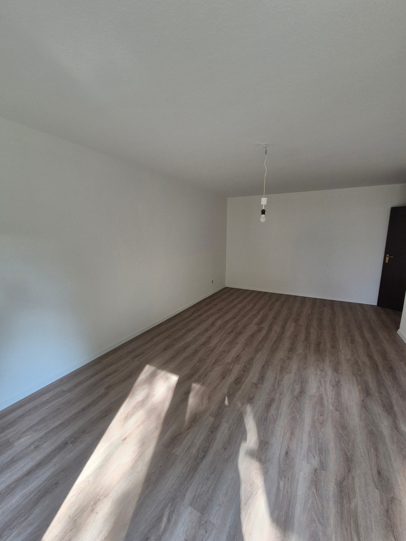 Großes leeres Zimmer mit Vinylboden, bereit zur Übergabe